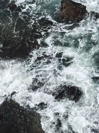 High angle view of wave splashing on rocks