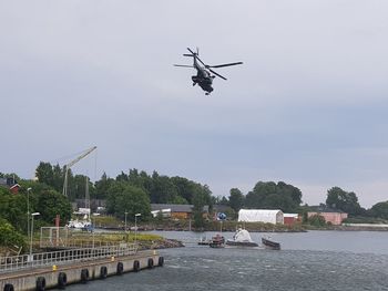 Low angle view of helicopter flying over river against sky