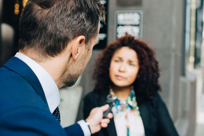 Rear view of businessman taking interview of businesswoman in city