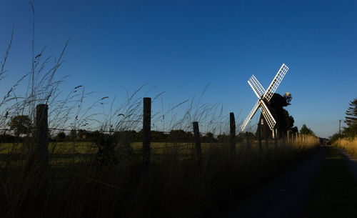 Traditional windmill on field against clear blue sky