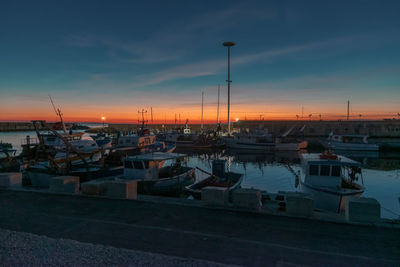 Boats moored at harbor during sunset