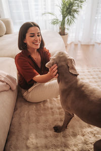 Portrait of young woman with dog on bed at home
