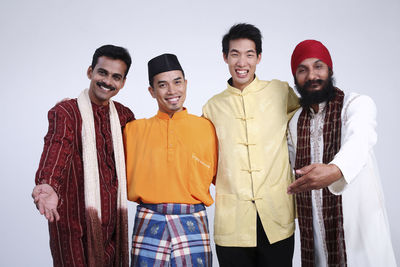 Portrait of happy male friends standing in traditional clothing against white background