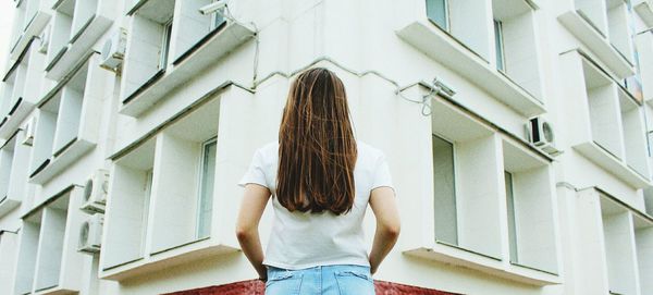 Rear view of woman standing against building