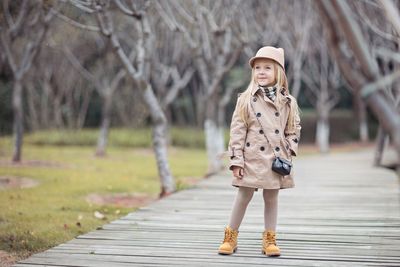 Girl looking away standing on footpath at park