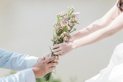 Cropped image of hands giving flowers to bride