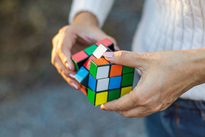 Midsection of woman playing with puzzle cube