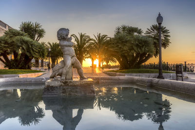 Reflection of sculpture in pond against sky at balcon del mediterraneo during sunrise