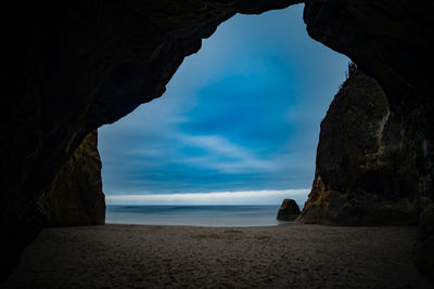 Rock formation on beach against sky