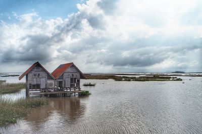 Houses by lake against sky