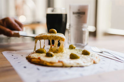 Close-up of human hand holding pizza slice on table