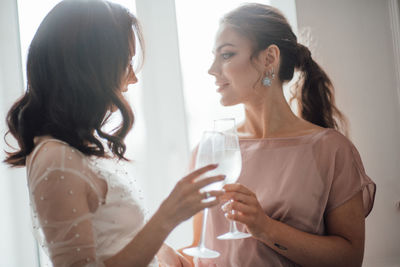 Bridesmaid and bride holding champagne flute