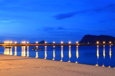 Illuminated bridge over sea against sky at night