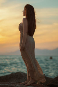 Woman standing at beach during sunset