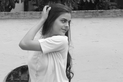 Portrait of young woman standing against wall