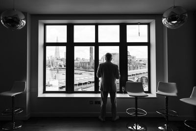 Rear view of man standing against window