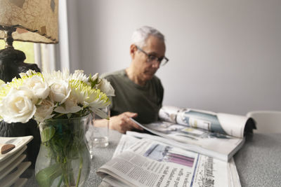 Close-up of senior man reading books while sitting on table at home