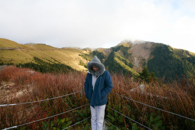 Woman standing by railing against plants during winter