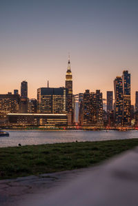 Buildings by river against sky during sunset