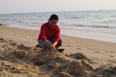 Full length of woman making sandcastle at beach