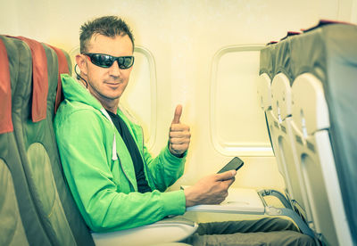 Portrait of man gesturing while sitting in airplane