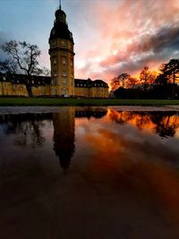 Reflection of building in lake against sky during sunset
