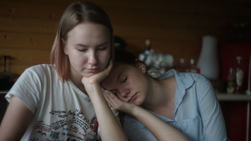 Close-up of woman leaning on sister at home