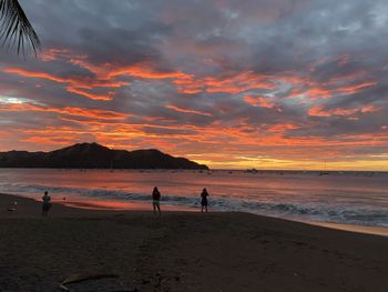 People on beach against sky during sunset