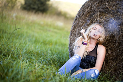 Woman smoking while sitting on field