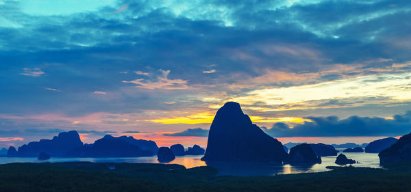 Silhouette rocks by sea against sky during sunset