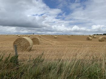 Hay bales on field against sky