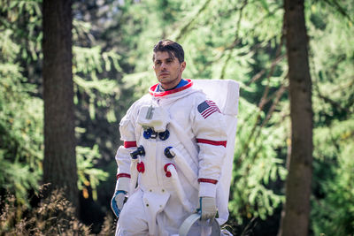 Astronaut looking away while standing in forest