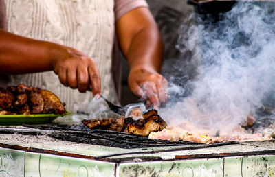 A woman grilling meat for sale at a local market in indonesia