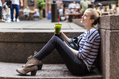 Usa, new york city, smiling woman having a break drinking a smoothie in manhattan