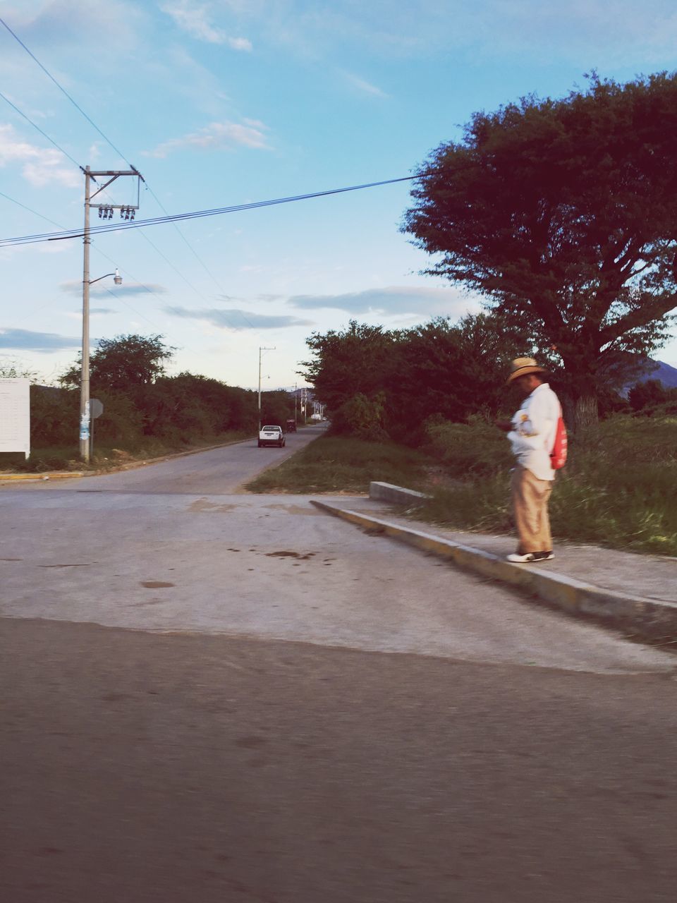 full length, tree, rear view, the way forward, transportation, road, sky, lifestyles, street, walking, leisure activity, diminishing perspective, men, country road, on the move, vanishing point, power line, casual clothing