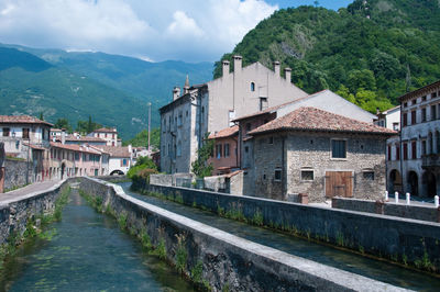 River amidst buildings and mountains against sky