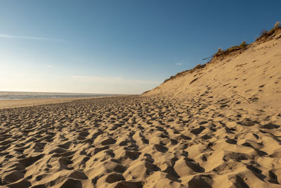 Scenic view of sand dune on beach against sky