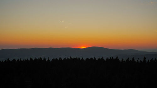 Scenic view of silhouette mountains against orange sky