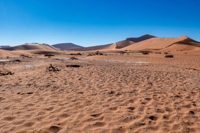Sand dunes in desert against clear blue sky