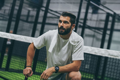 Man playing padel tennis, racket in hand wipes the sweat. young sporty boy at the end of the match. 