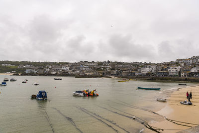 Boats in sea by buildings against sky