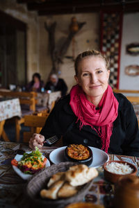 Portrait of smiling woman having food at table in restaurant