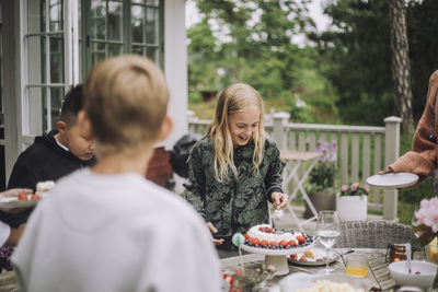 Girl cutting birthday cake while standing near table