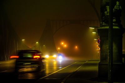 Cars in illuminated tunnel at night