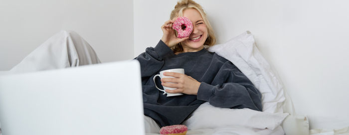 Young woman using laptop while sitting on bed at home
