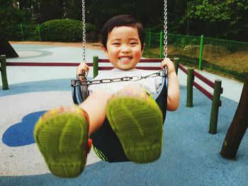 Portrait of smiling boy swinging at playground
