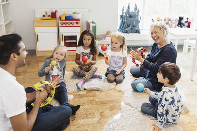 Happy teachers and children holding musical instruments in classroom