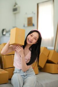 Portrait of young woman using mobile phone while sitting on sofa at home