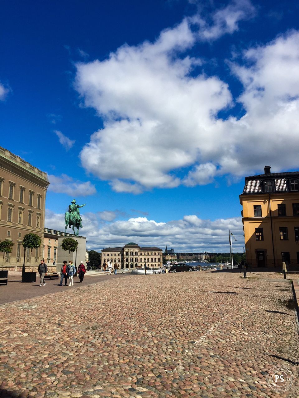 GROUP OF PEOPLE ON STREET BY BUILDINGS AGAINST SKY