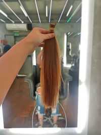 Cropped hand of woman holding hair in barber shop